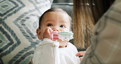 Buy stock photo Child, baby girl and biting toys in living room with mom, home and development, growth and teething progress. Kid, face and chewing rattle in mouth for tooth, gums and playing in house lounge
