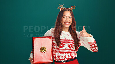 Buy stock photo Christmas, gift and thumbs up with portrait of woman in studio for celebration, motivation or success. Box, present and smile of happy person on green background for festive holiday or tradition