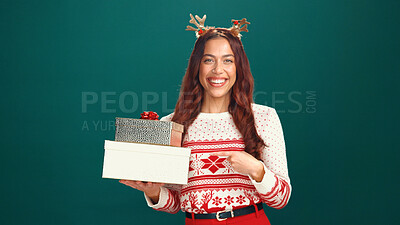 Buy stock photo Christmas, gift and pointing with portrait of woman in studio for holiday season, celebration or smile. Festive event, xmas vacation and present with person on green background for space and December