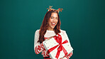 Christmas, portrait or happy woman with gift box in studio for holiday celebration with mockup space. Smile, person and present for xmas, festive tradition or laugh with giveaway on green background