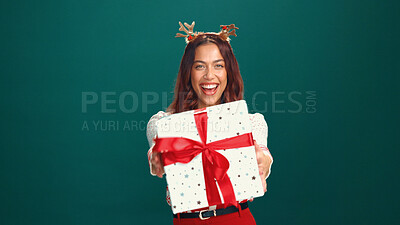 Buy stock photo Christmas, portrait and happy woman offer gift in studio, holiday surprise and celebration. Smile, person and giving present for xmas, festive giveaway and laugh on green background with mockup space