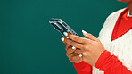 Christmas, phone and hands of woman in studio with networking, communication or social media. Mockup space, xmas contact and person with cellphone for online, app or texting by green background.