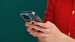 Christmas, cellphone and hands of woman in studio with networking, communication or social media. Technology, xmas contact and person with phone for online, mobile app or texting by green background.