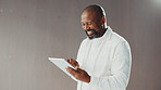 Mature businessman, tablet and wall at office, smile and scroll with mockup space for contact on web. African person, editor and writer with application, happy and report with article at media agency
