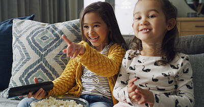 Buy stock photo Pointing, popcorn and watching TV with girls on sofa in living room of home together for streaming. Eating, remote and smile with sister children in apartment for bonding or television entertainment