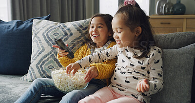 Buy stock photo Popcorn, smile and watching TV with girls on sofa in living room of home together for streaming. Eating, relax and remote with sister children in apartment for bonding or television entertainment