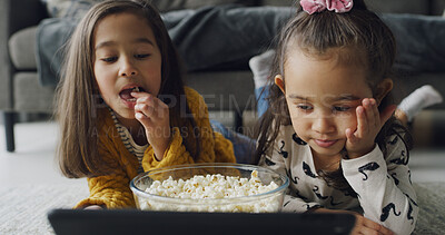 Buy stock photo Popcorn, relax and tablet with girls on floor in living room of home for subscription service. App, eating and streaming with sister children in apartment together for bonding or video entertainment