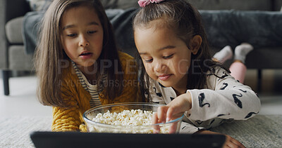 Buy stock photo Popcorn, tablet and watching with girls on floor in living room of home for subscription service. App, eating and video streaming with sister kids in apartment together for bonding or entertainment