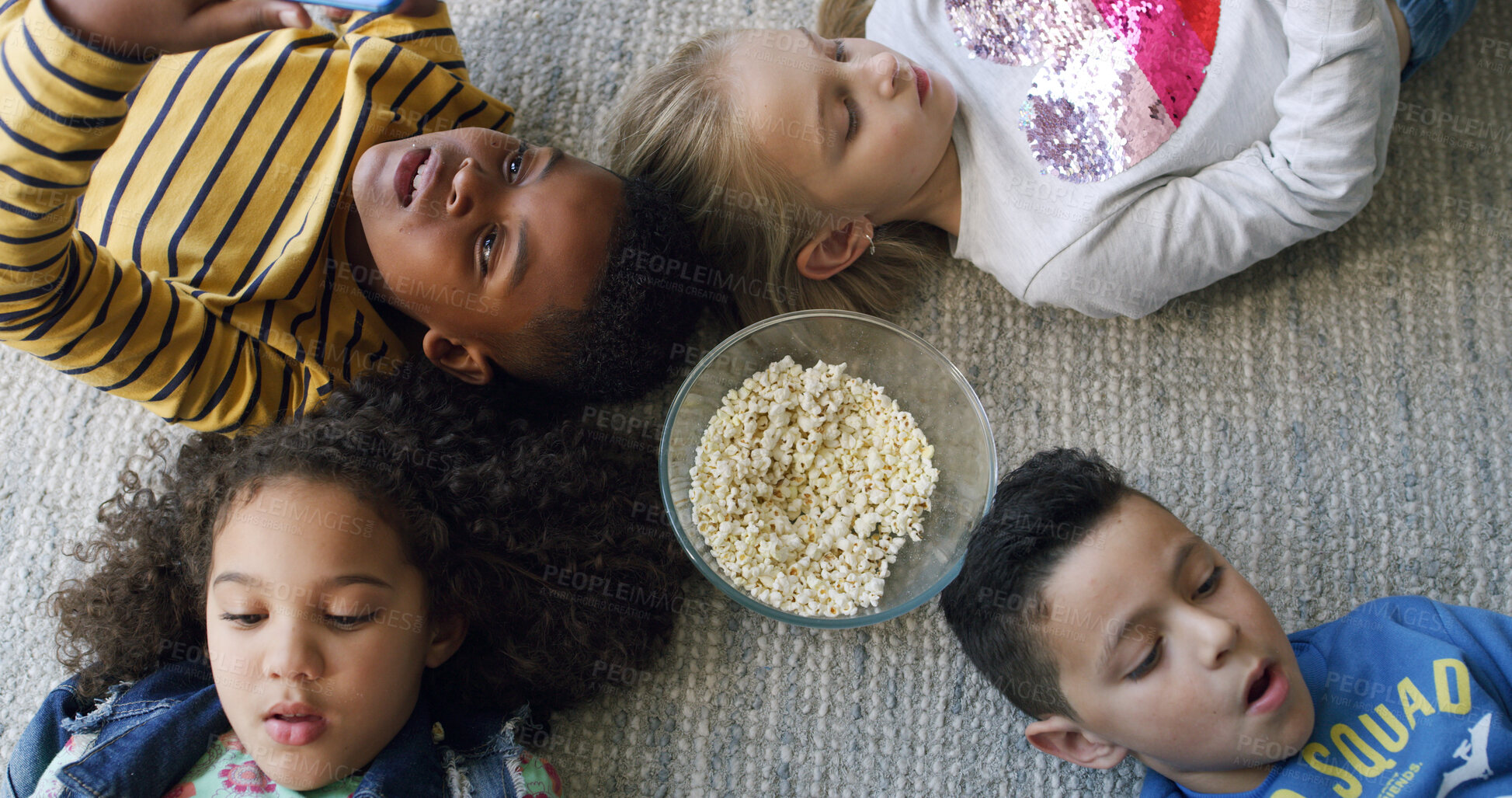 Buy stock photo Popcorn, media and group of children on floor in home for playing online games on app together. Friends, technology and top view of kids with snack and cellphone for watching movie or show in house.