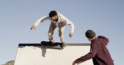 Buy stock photo Man, skateboard and trick on ramp at park with friends, outdoor and culture with streetwear in city. People, skater team and training with balance, speed and low angle with sky for extreme sports