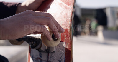 Buy stock photo Hands, skateboard and check wheel for maintenance, repair bearings and inspection outdoor in city. Skater, sports and person fix with deck, equipment or tuning with gear adjustment at urban skatepark