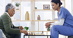 Nurse, elderly woman and play chess in home, smile and solution with cognitive function. Senior person, caregiver and challenge with board game, relax and competition for brain health in retirement