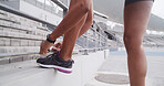 Shoes, laces and person hands on stadium, prepare for running or sports for workout on race track. Fitness, athlete or sprinter legs at arena for practice, training and start cardio exercise outdoor