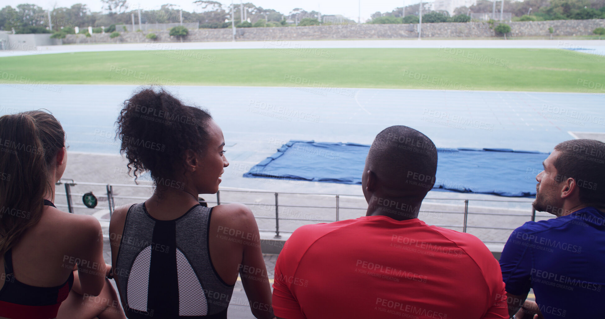 Buy stock photo Talking, team and athlete on break, stadium or people on bleachers for competition or communication. Back, fitness and view of sports field, rest and runner with sportswear, wellness and outdoor