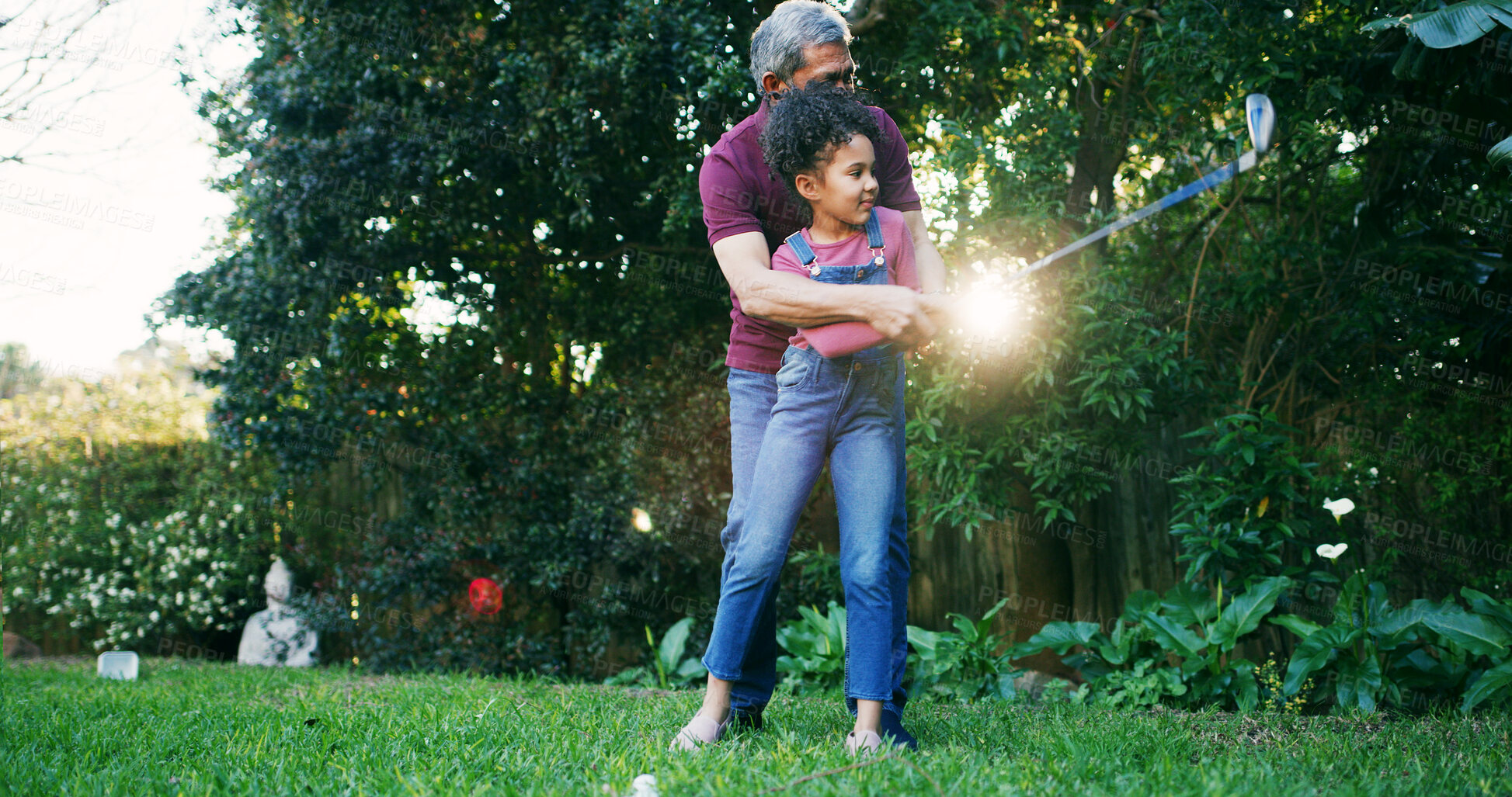 Buy stock photo Golf, teaching and grandfather with kid in nature for swing, target practice and support together. Sports prodigy, learning and game mentor with old man and girl in backyard of home for put and hobby