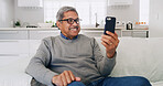 Happy, senior man and phone on sofa for watching online video, social media post or reading ebook. Retirement, elderly person and relax with smartphone in home for streaming subscription and browsing