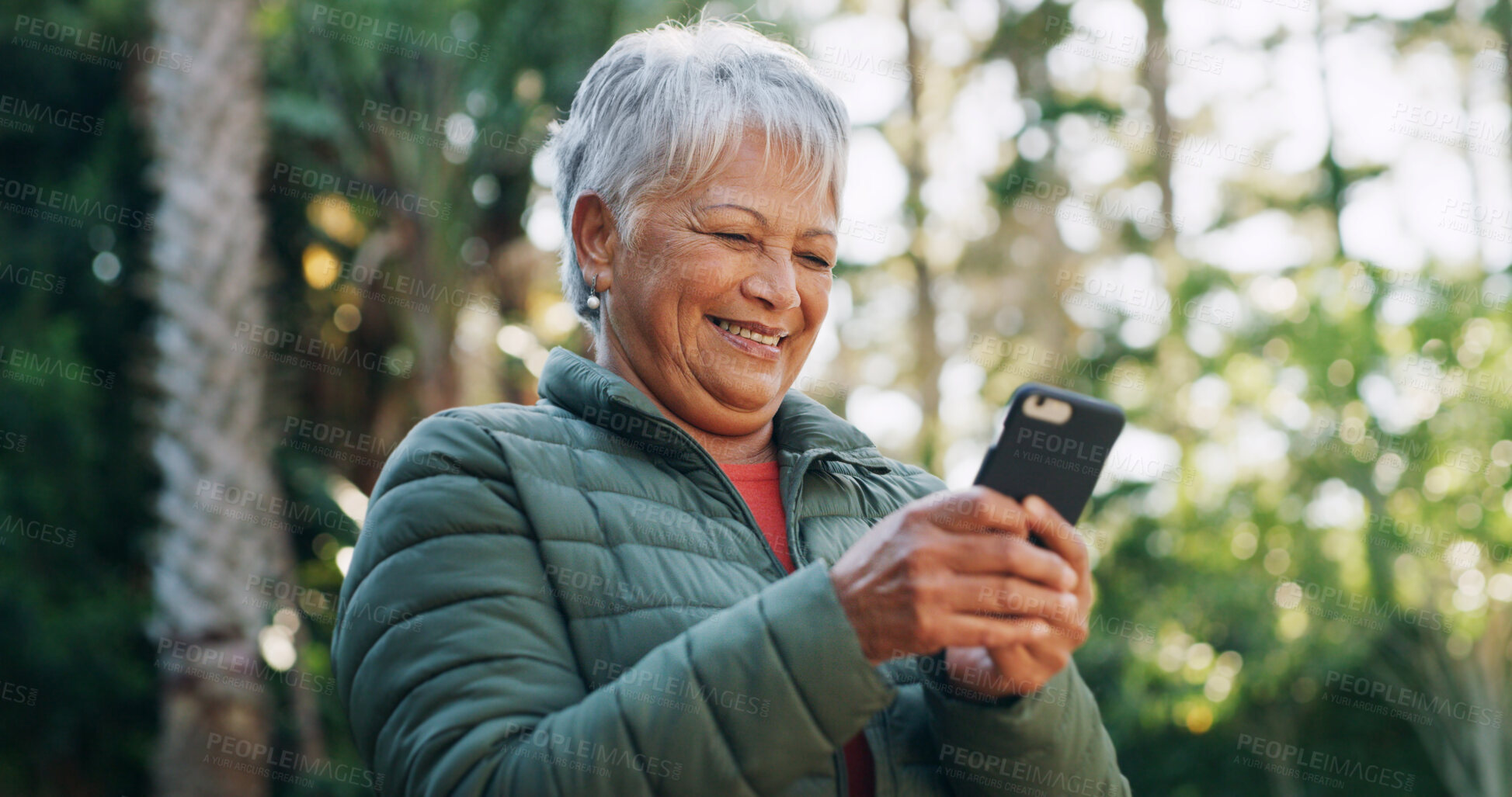 Buy stock photo Nature, happy and senior woman with phone for texting, communication or mobile app for weekend trip. Smile, forest and elderly female person with cellphone for chatting online outdoor on holiday.