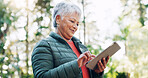 Nature, happy and senior woman with tablet for texting, communication or mobile app for weekend trip. Smile, forest and elderly female person with technology for chatting online outdoor on holiday.