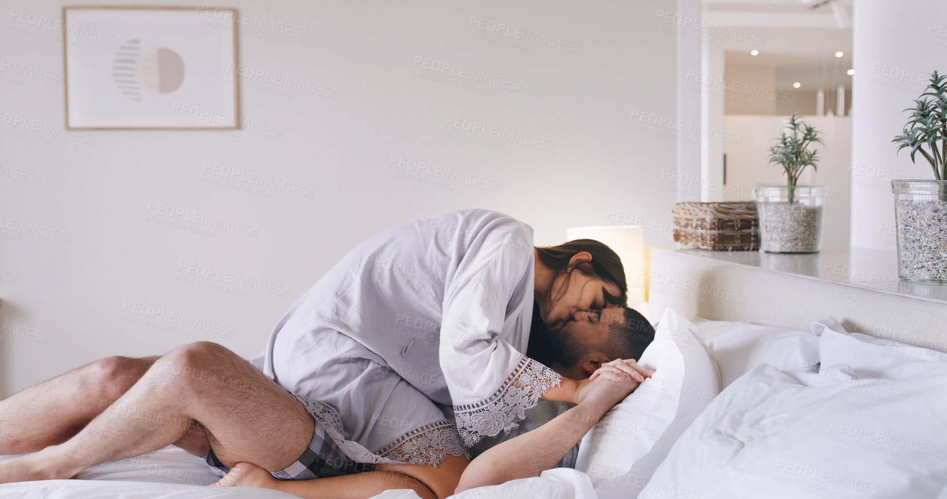 Buy stock photo Couple, rest and kiss on bed at house for love, romance and calm morning on honeymoon. People, relax and intimate with partner, affection and bonding together for marriage commitment at accommodation