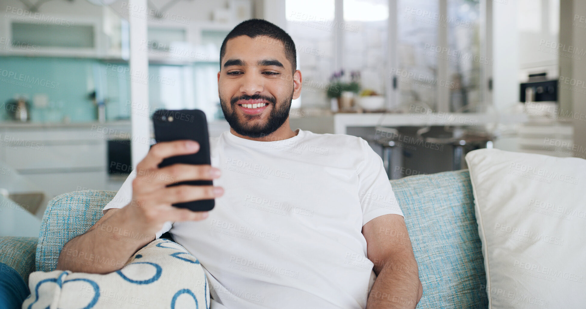 Buy stock photo Home, smartphone and man on sofa, smile and relax with social media, internet and network. Funny meme, communication or person on couch, cellphone or message to contact or digital app for texting