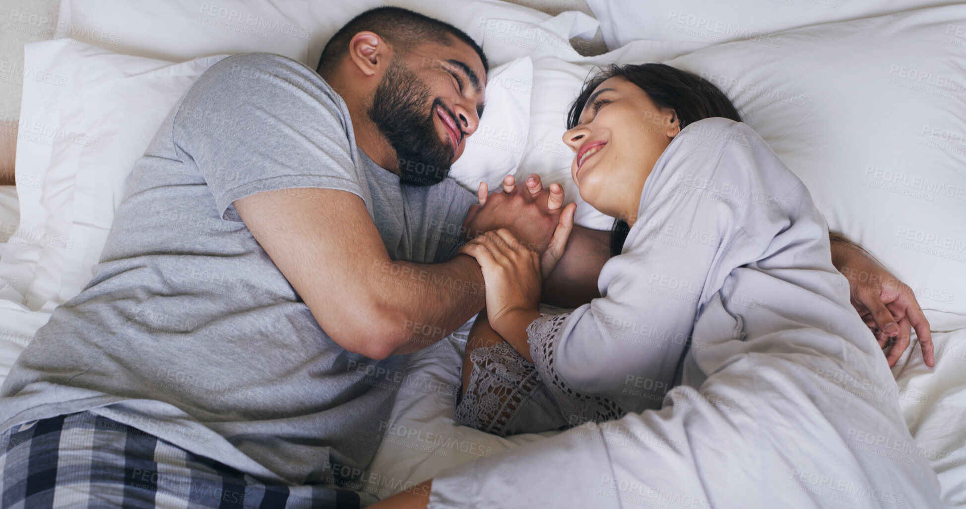 Buy stock photo Smile, couple and relax on bed at house with love, wake up and calm morning on honeymoon. Above, people and rest with holding hands for romance, affection and bonding together for marriage commitment