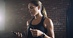 Tired, earphones and woman in gym, fitness and smartphone with music playlist, app and training. Cellphone, exercise and healthy person in wellness center, audio and listening to sound and fatigue