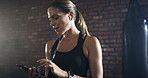 Tired, earphones and woman in gym, exercise and cellphone with music playlist, app and fitness. Smartphone, exhausted and healthy person in wellness center, radio and listening to sound and fatigue