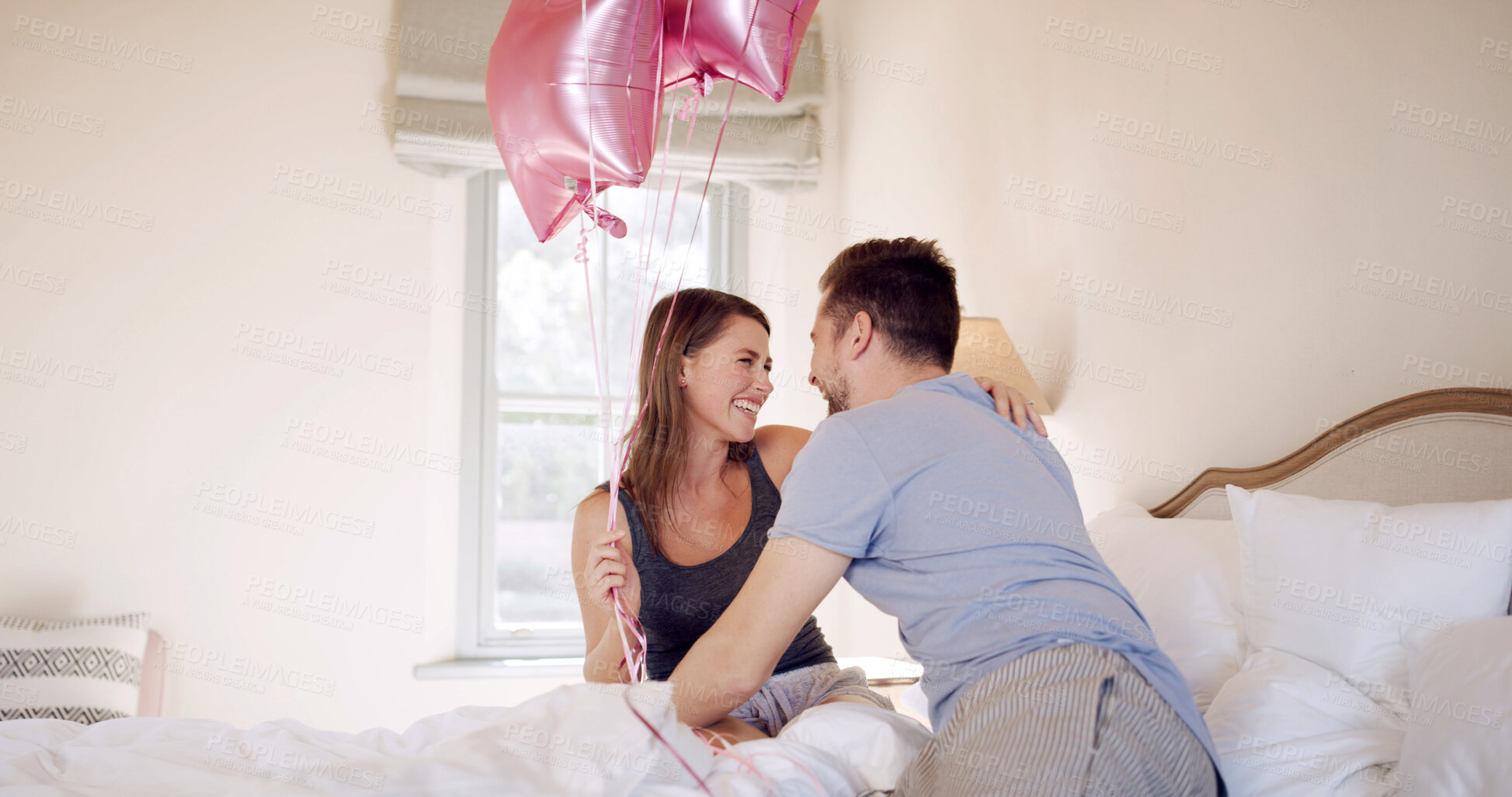 Buy stock photo Happy, couple and celebration with balloons in bedroom, hug and bonding on anniversary in apartment. Love, man and gift for woman on special day, romance and affection on bed or together in house