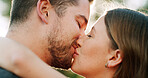 Hug, kiss and couple in park for love, bonding and romantic relationship together on weekend. Dating, nature and man with woman with affection for commitment, trust and celebrate anniversary outdoor