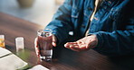 Hands, pills and man with glass of water for medical treatment, prescription and tablets for recovery. House, health and person with medication container for vitamins, supplements and drugs on table