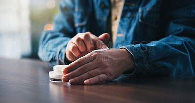 Buy stock photo Skincare, person and apply cream on hands for hydration, dermatology or dermatitis condition in home. Lotion, product or cosmetics application for dry skin, moisturizer or healing for eczema on table