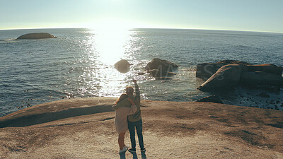 Buy stock photo Hug, pointing and back of couple by ocean to relax on holiday, vacation and weekend together. Dating, travel and man with woman embrace by sea, water and sunshine for bonding, relationship or above