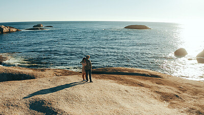 Buy stock photo Space, rocks and couple hug by ocean for holiday, vacation and weekend together. Dating, travel and back of man with woman embrace by sea, water and horizon for bonding, relationship and romance