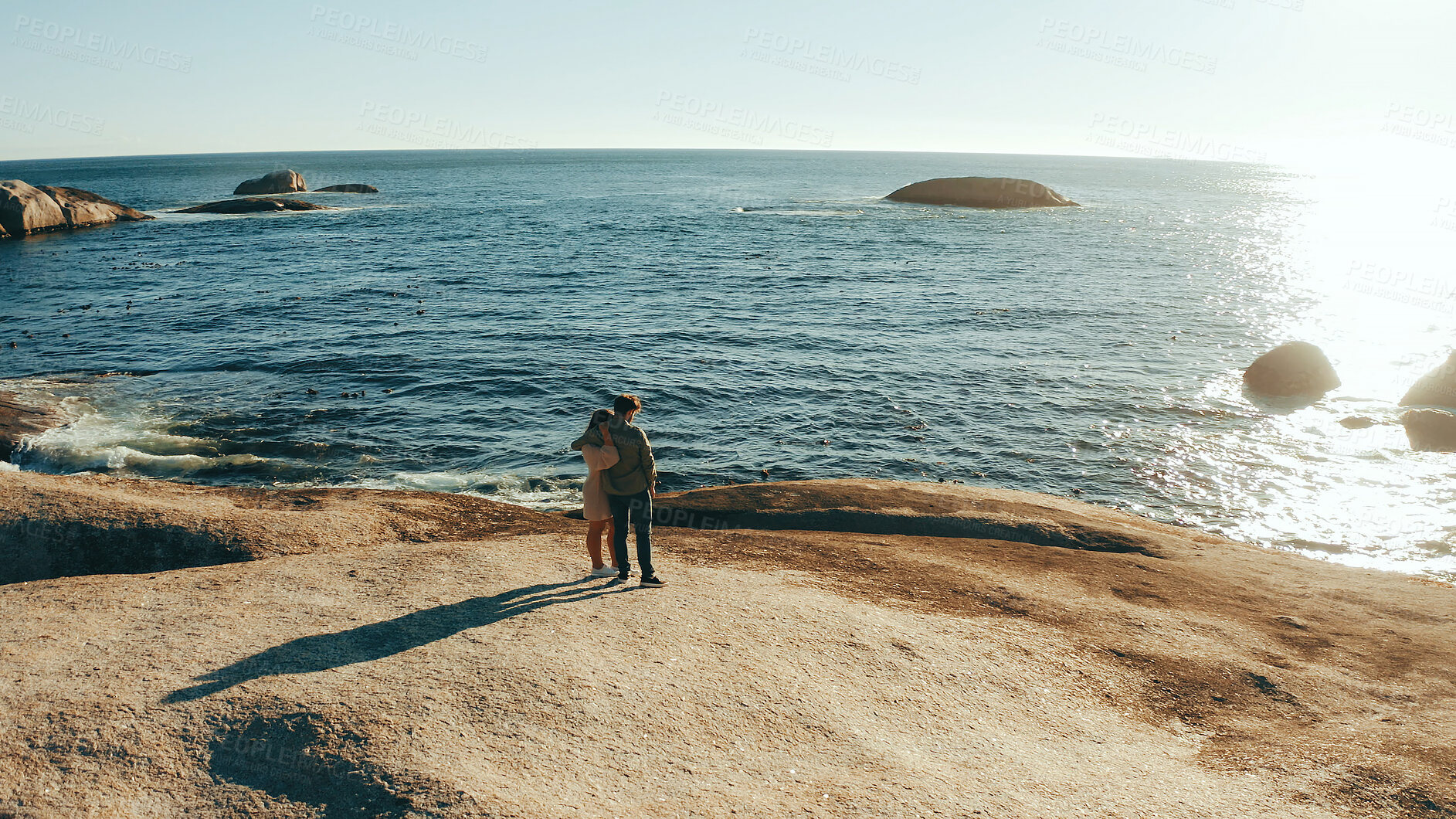 Buy stock photo Space, rocks and couple hug by ocean for holiday, vacation and weekend together. Dating, travel and back of man with woman embrace by sea, water and horizon for bonding, relationship and romance