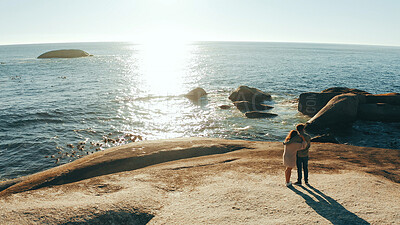 Buy stock photo Couple, hug and back with ocean view in summer, rock and above with sightseeing on vacation with lens flare. Man, woman and embrace for memory, sea or love with bonding outdoor on holiday in Greece