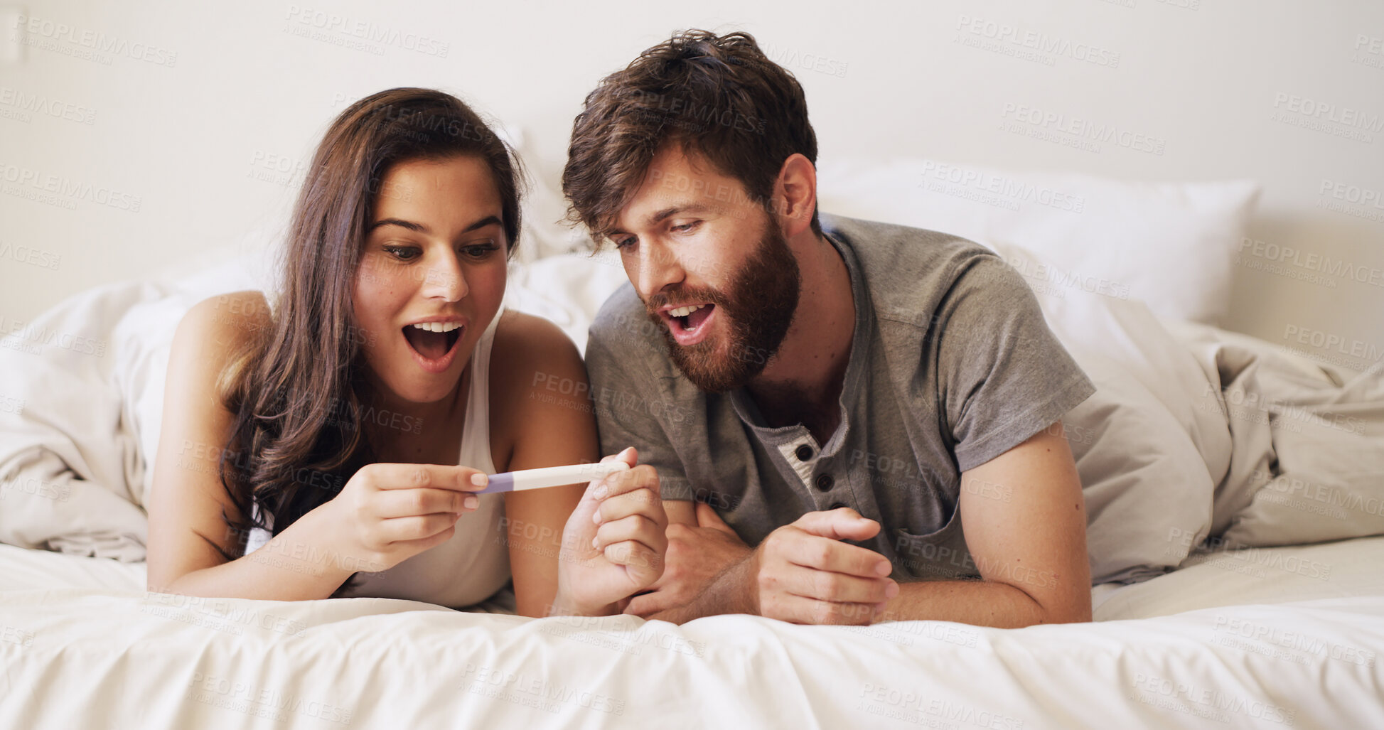 Buy stock photo Surprise, love and couple with pregnancy test on bed for future, family or baby together in home. Shock, bonding and man with woman for positive pregnant kit with excitement in marriage or bedroom.