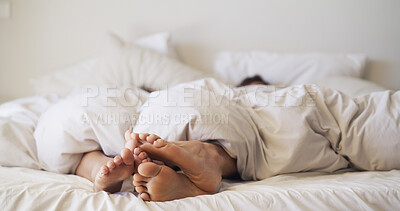 Buy stock photo Feet, love and couple relax in bedroom for rest, peace and blanket for comfort in morning. Barefoot, people and touch in bed together on mattress with nap, sleeping and break on weekend in house