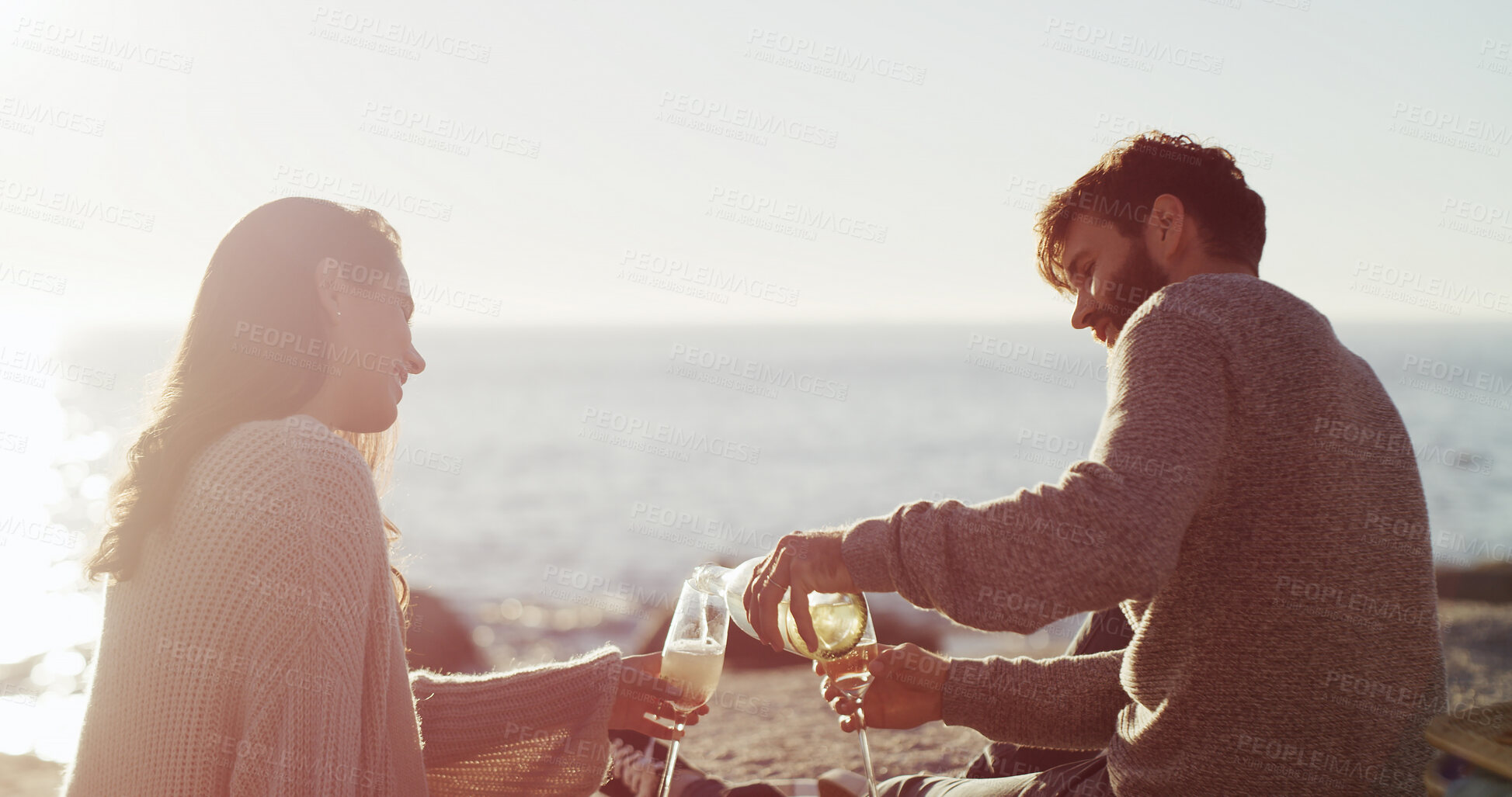 Buy stock photo Beach, picnic and couple with love, alcohol and bonding together with vacation, date or romance. Ocean, champagne or man with woman, anniversary or celebration with holiday, honeymoon or relationship