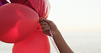 Hand, beach and balloons for love with valentines day celebration, holiday and space outdoor. Romantic gesture, inflatable and person at ocean for care, gift or present on vacation by sea for travel