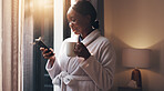 Coffee, phone and black woman by window in home with networking, social media or contact in morning. Happy, cappuccino and African female person with cellphone for communication on mobile app.