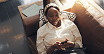 Black woman, smile and relax with phone on sofa for social media browsing, online news and streaming. Above, comfortable and person with smartphone in home for app download and scrolling dating site
