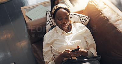 Buy stock photo Black woman, smile and relax with phone on sofa for social media browsing, online news and streaming. Above, comfortable and person with smartphone in home for app download, scrolling and dating site