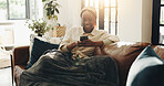 Black woman, happy and relax with phone on sofa for social media post, online news and texting. Comfortable, blanket and person with smartphone in home for app download, dating site and communication