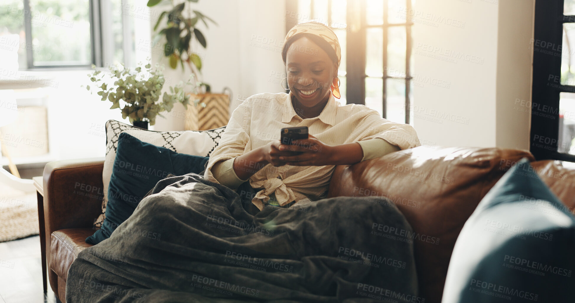 Buy stock photo Black woman, happy and relax with phone on sofa for social media post, online news and texting. Comfortable, blanket and person with smartphone in home for app download, dating site and communication