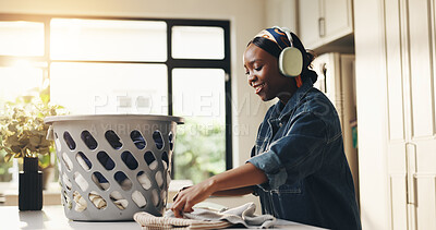 Buy stock photo Home, woman and streaming with headphones, laundry and smile for clean fabric and chores in kitchen. Happy, black person and listen to song with tech, housework or basket with clothes, audio or music