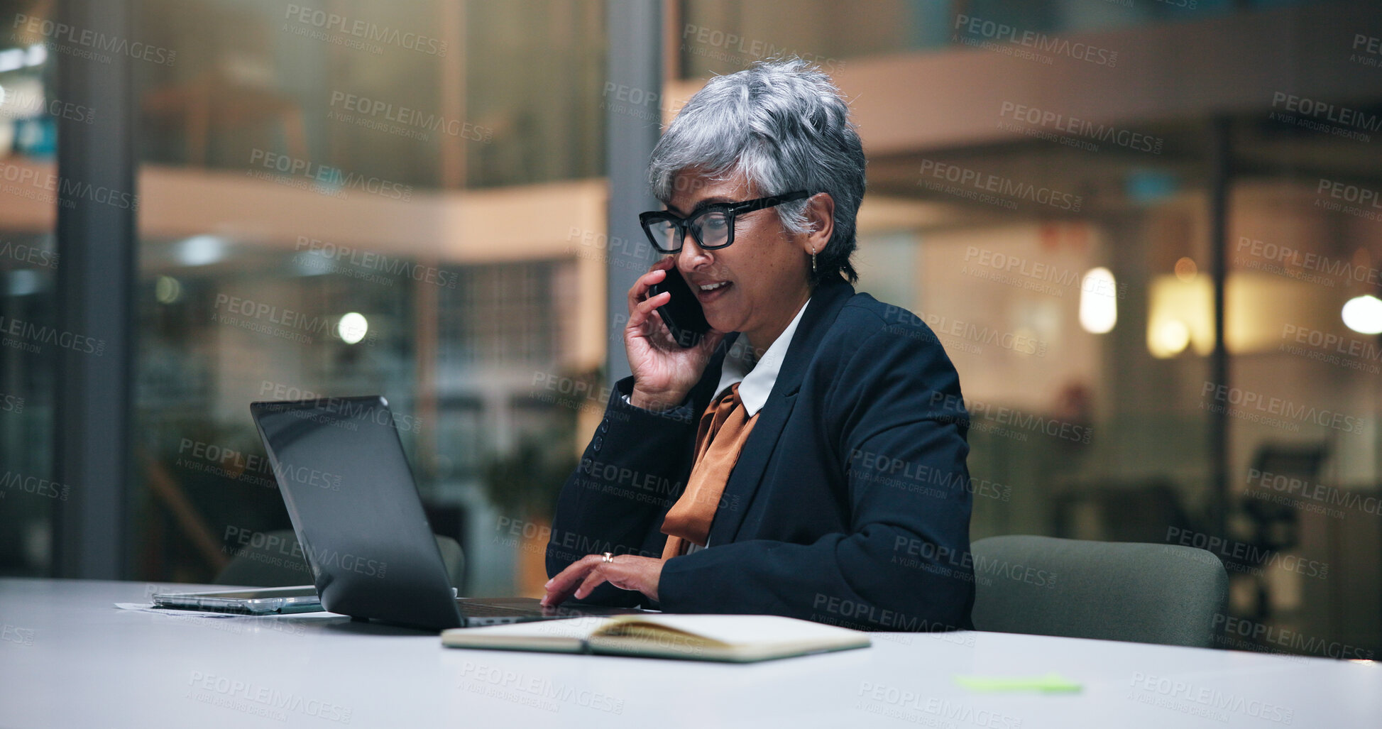 Buy stock photo Mature, business woman and night with phone call for finance, proposal or negotiation in office. Female person, accountant or financial advisor working late with laptop on mobile smartphone for deal