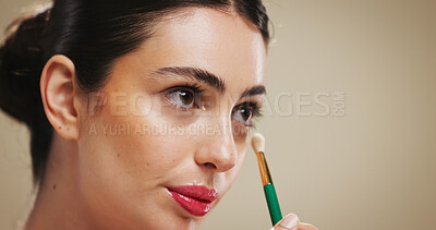 Buy stock photo Makeup brush, beauty and woman apply concealer for glow, aesthetic and makeover. Cosmetics, model and tools for foundation, product and facial transformation process on brown studio background space