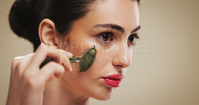 Buy stock photo Beauty, skincare and woman with jade roller on face for lymphatic drainage, skin glow and routine. Mockup space, person and cosmetics tool on studio background for grooming, radiance and self care
