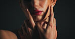 Beauty, hands and mouth of model on black background for cosmetics, dermatology or wellness. Lipstick, skincare and touch with woman in dark studio for facial aesthetic, satisfaction or treatment