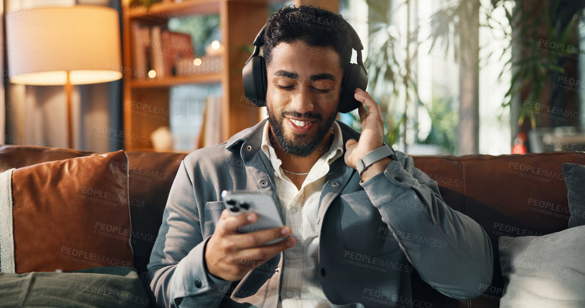 Buy stock photo Happy, man and phone with headphones on sofa for streaming subscription, audio playlist or song. Smile, person and relax with smartphone in lounge for listening to radio and feel good album in home